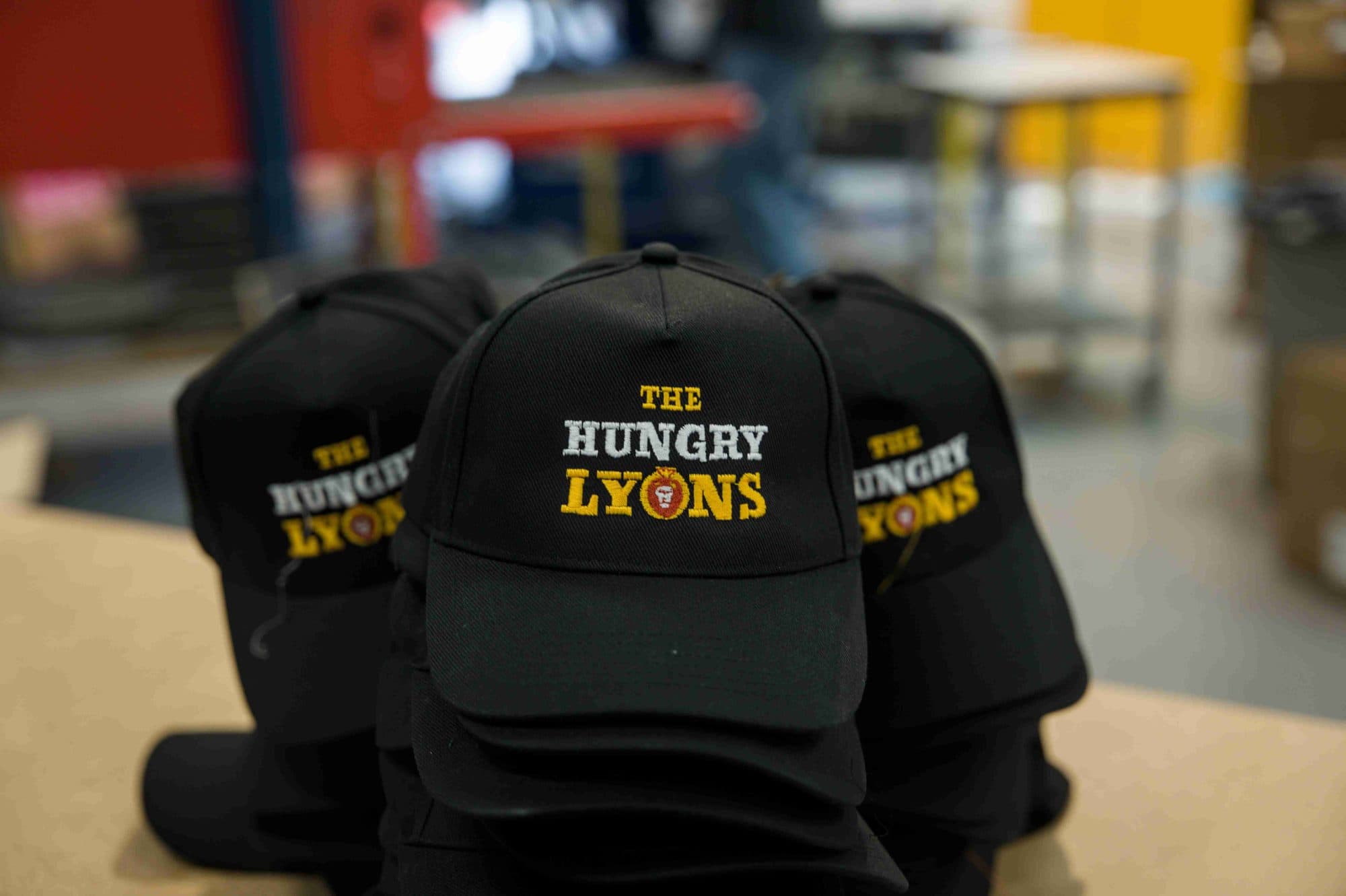 A stack of black caps with embroidered logos on a packing table in the factory