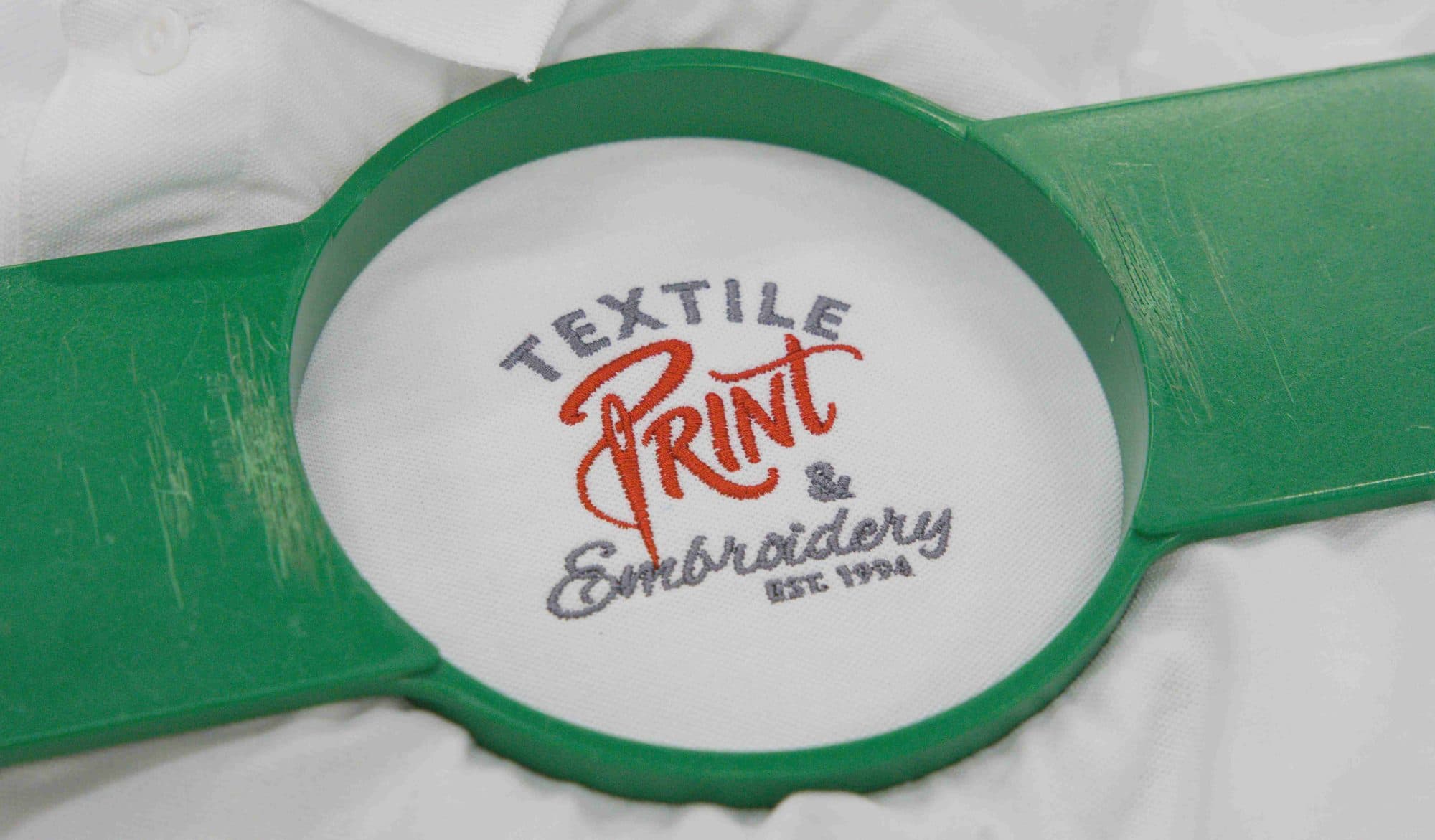 Close up of embroidered lettering inside a green embroidery hoop