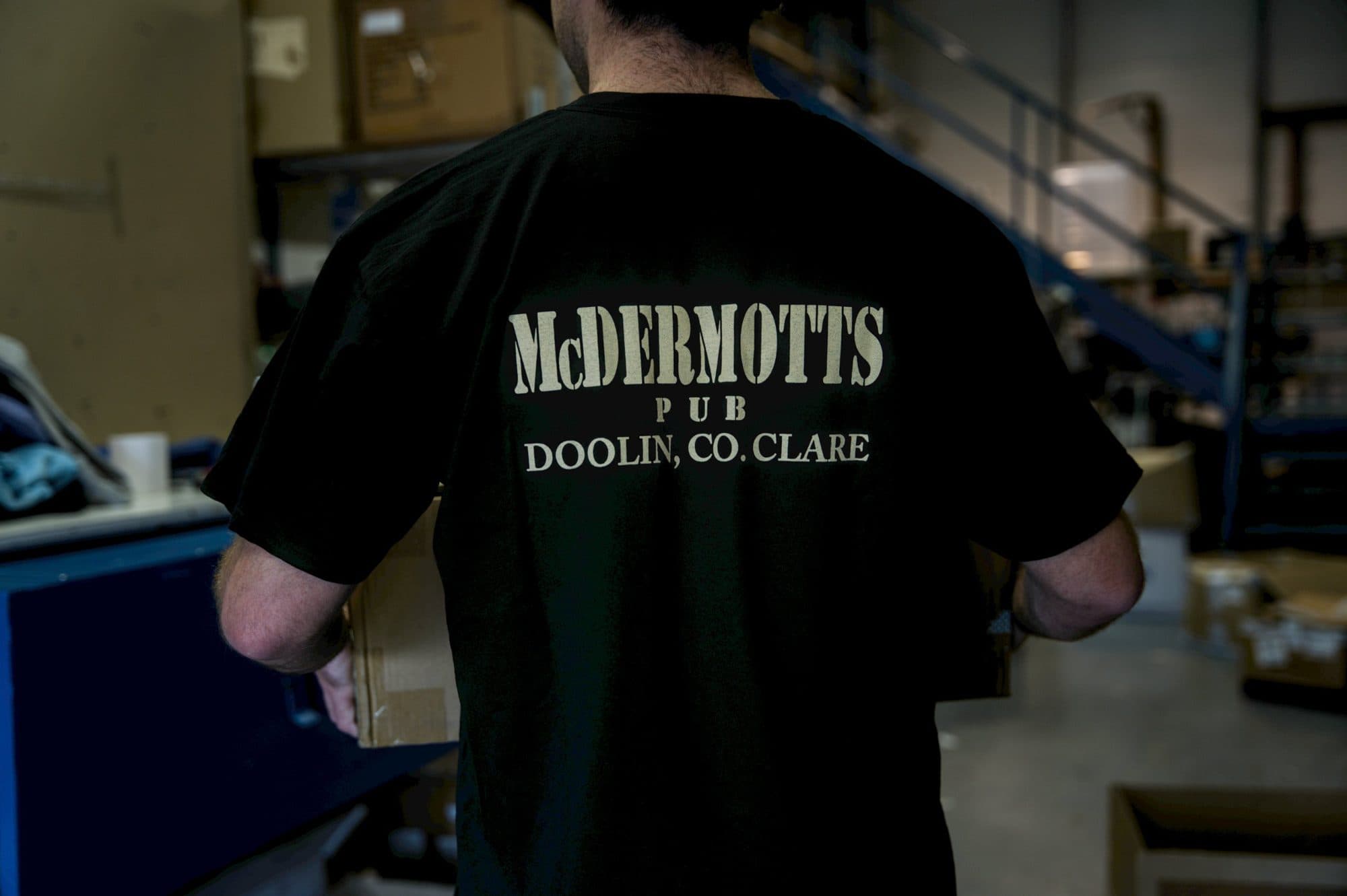 Screen printed black T shirt worn while carrying a box through our warehouse